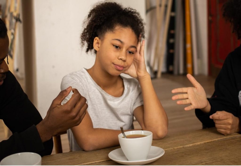 child sitting at table with a coffee upset