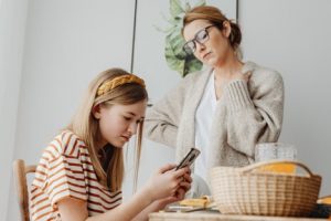 mother watching over daughter on phone